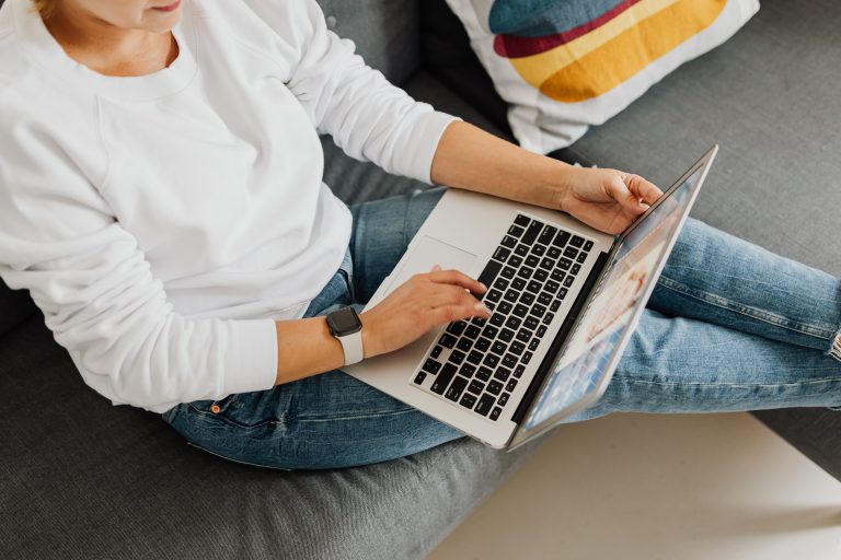Person typing on a laptop while sitting on a couch