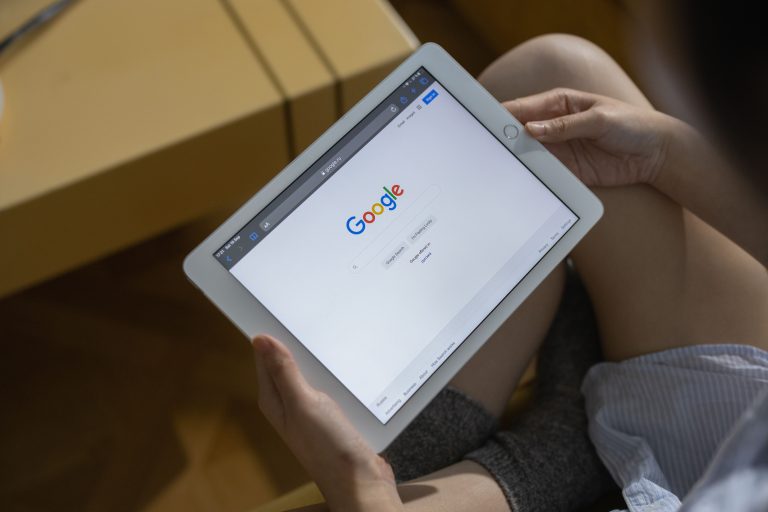 Close-up of hands holding a tablet showing the Google search page